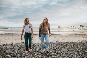 two girls who wear environmentally safe sunscreen on their noses and walking in the beach